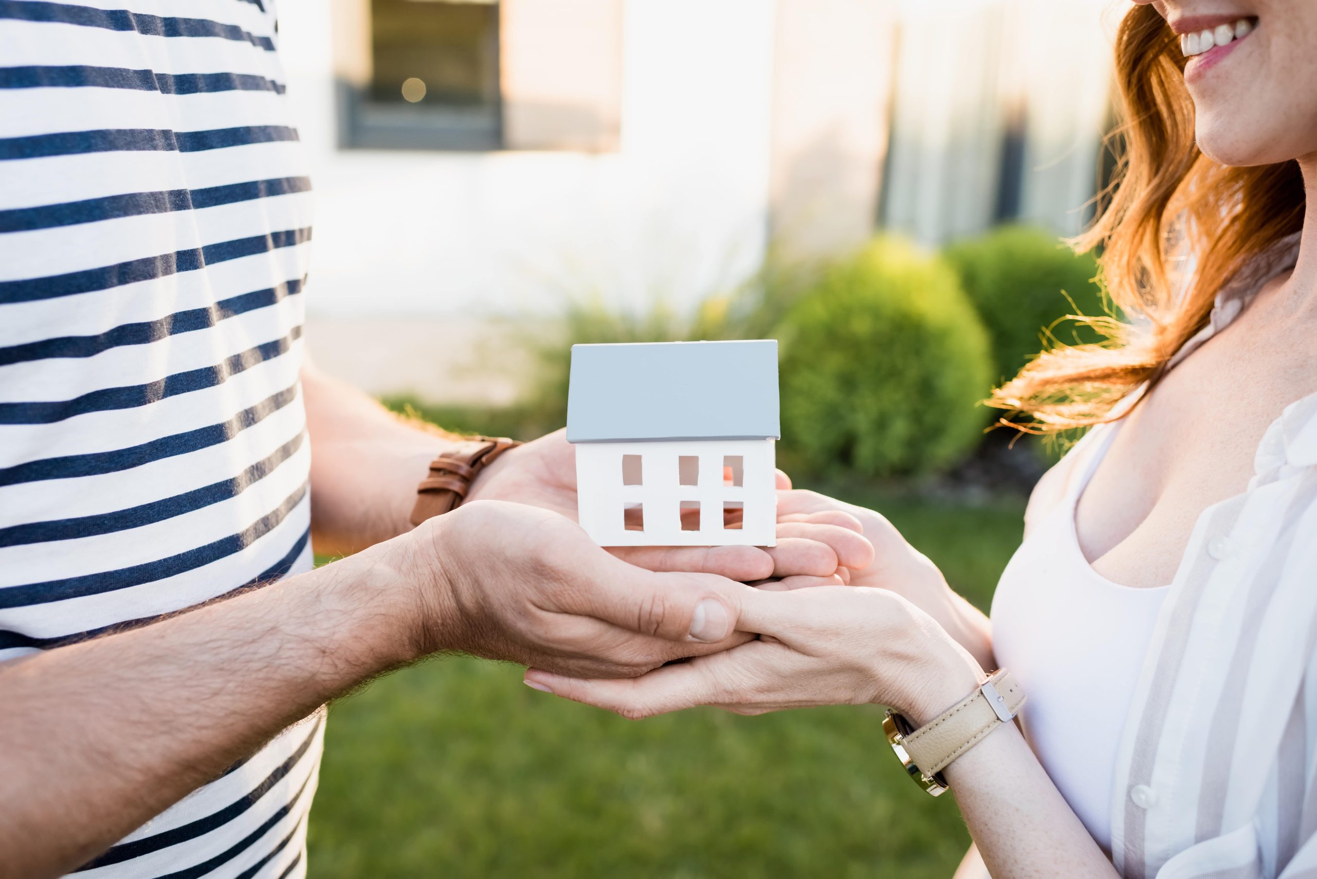 A young couple holding a model house in their hands A young couple holding a model house in their hands